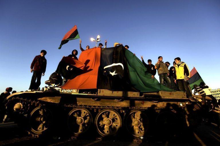 Anti-Gaddafi rebels command a tank as gun battles continue across key cities