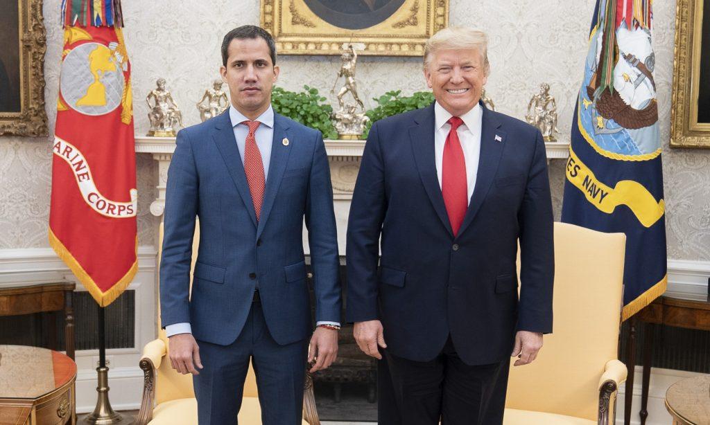 Two men in suits standing in front of a person in a chair

AI-generated content may be incorrect.