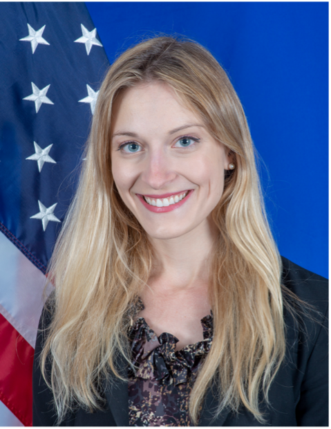 A person smiling in front of a flag
AI-generated content may be incorrect.