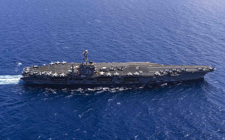 A view of the USS Harry S. Truman from above as it sails across a blue sea.