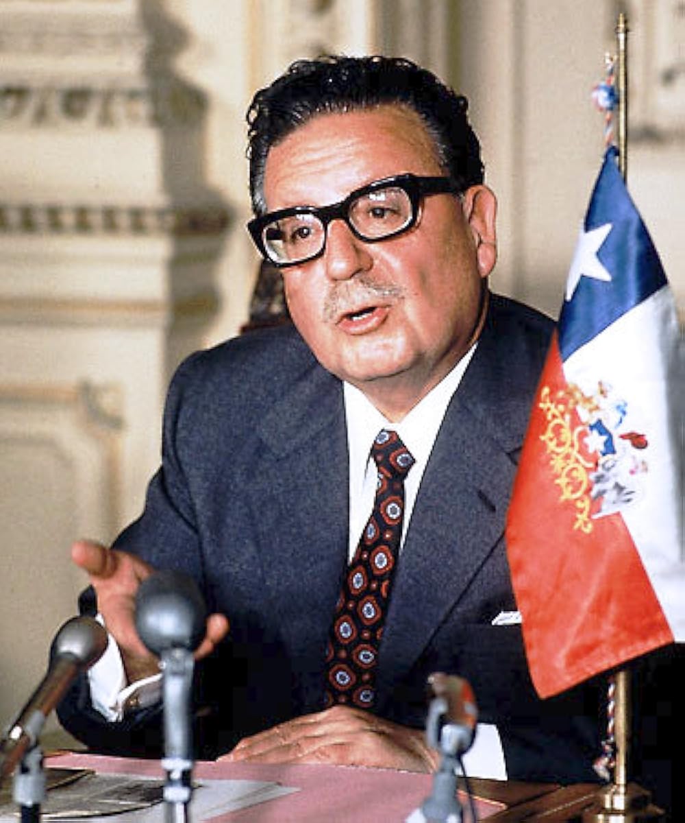 A person in a suit speaking into microphones

AI-generated content may be incorrect.