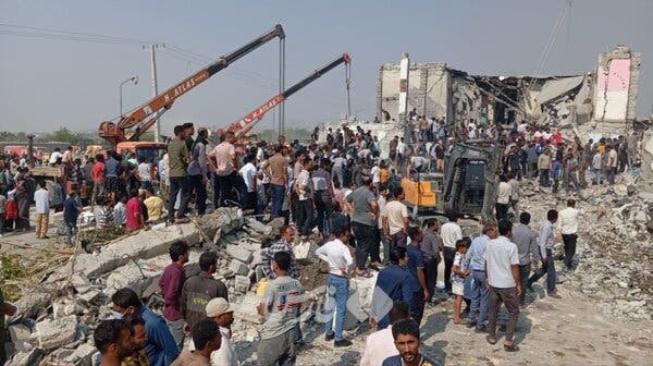 A group of people looks through the rubble of a building that was destroyed in a military strike.