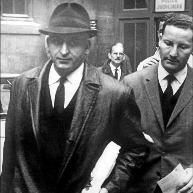 A person in a hat and suit walking down a street

AI-generated content may be incorrect.