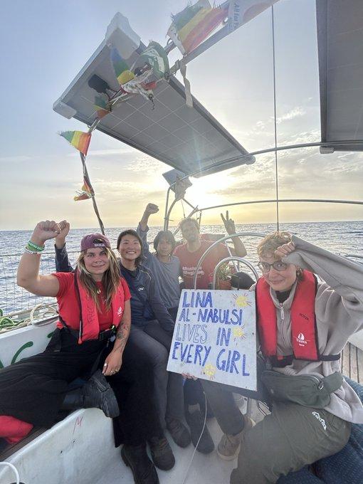 Photo of 5 international volunteers on board the #FreedomFlotilla sailing boat Lina Al-Nabulsi, headed towards Gaza today, as sun sets.
The sign they hold says "Lina Al-Nabulsi lives in every girl." 
Adjacent VIDEO of the boat from above says "You cannot sink a movement."  and then in smaller lettering, white on green background "The Lina Al-Nabulsi is currently the last boat of the fleet sailing towards Gaza to break the brutal, illegal siege. Above is a video of the crew yelling "Free Palestine!". We will keep sailing until the siege is broken and Palestine is free."   
+ Canadian Boat to Gaza logo.