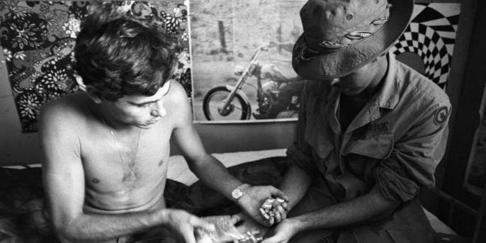 Two U.S. soldiers in Vietnam exchanging vials of heroin. (Credit: Bettmann Archive/Getty Images)