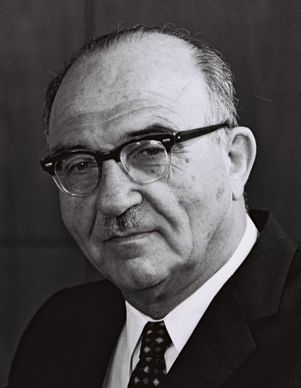 A person wearing glasses and a suit
AI-generated content may be incorrect.