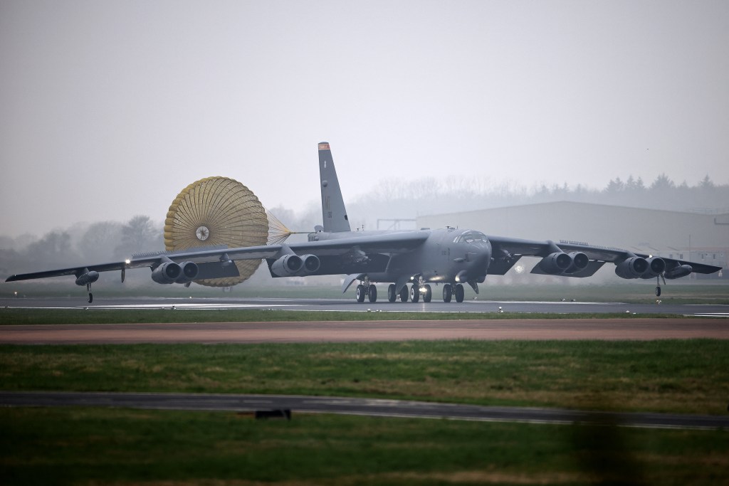 A US Air Force Boeing B-52 Stratofortress bomber jet lands on a runway.