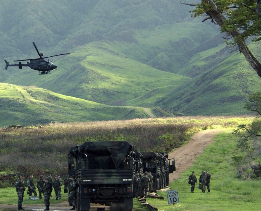 FILE - An Army Kiowa helicopter flies over a convoy of U.S. soldiers at the Mākua Military Reservation in Hawaiʻi, Dec. 8, 2003. In December 2023, the U.S. military confirmed that it will permanently end live-fire training in Mākua Valley on Oʻahu, in a major win for Native Hawaiian groups and environmentalists after decades of activism.