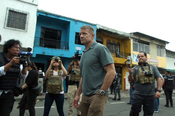 Erik Prince stands on a street, surrounded by people with cameras.
