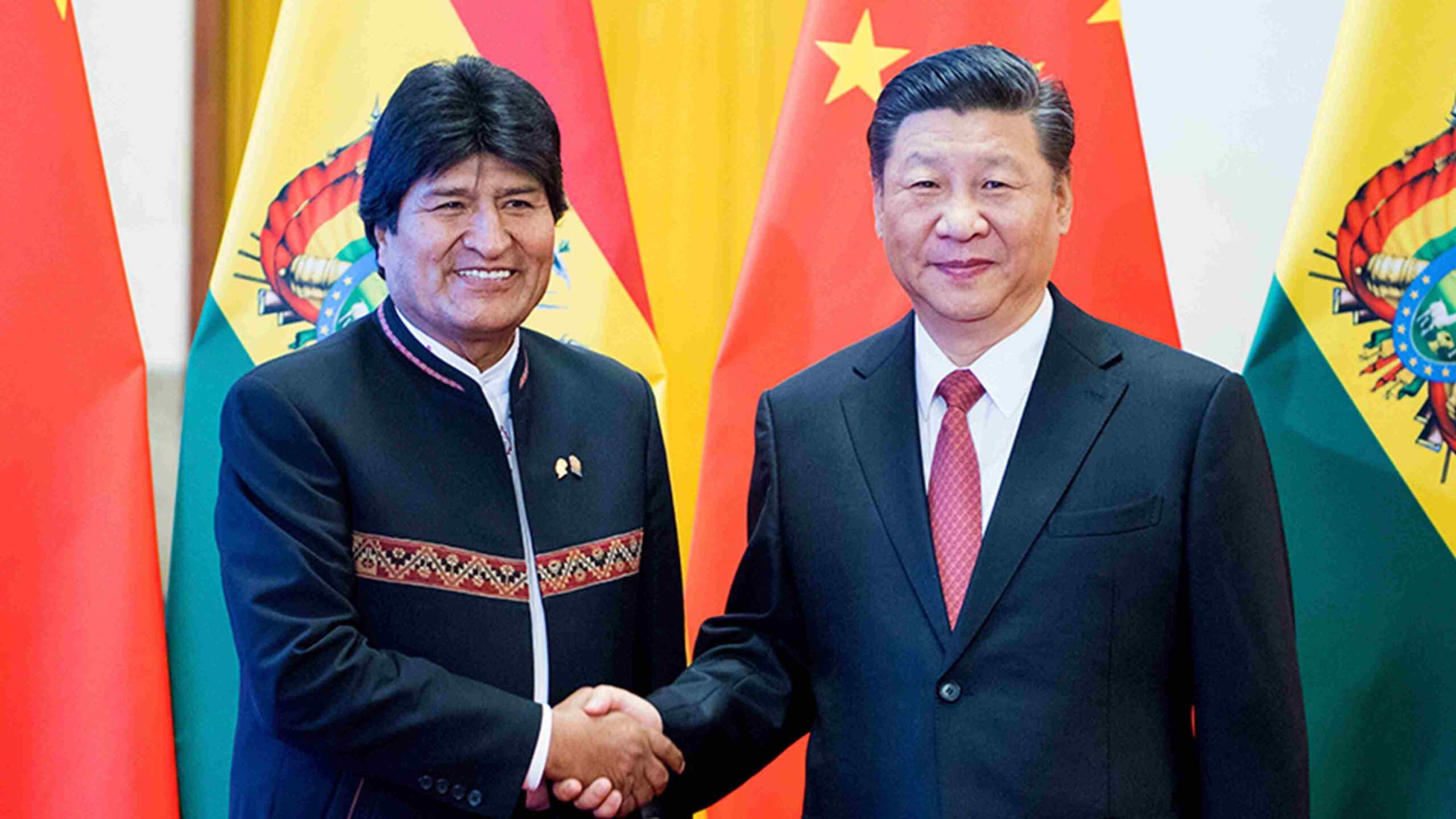 Two men shaking hands in front of flags

AI-generated content may be incorrect.