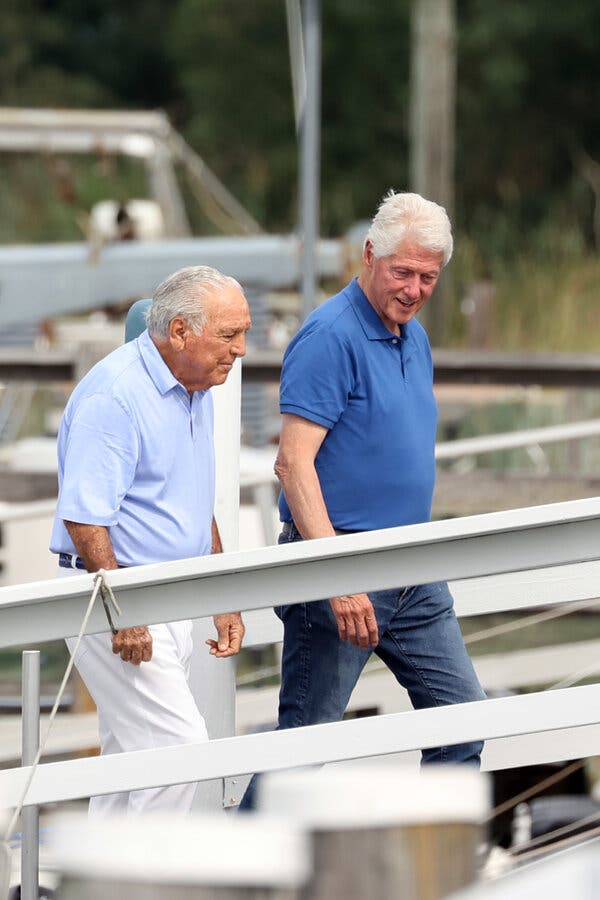 Two older men with gray hair and blue polo shirts walking side by side up what appears to be a boat ramp.